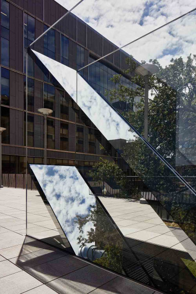 An image of Sarah Oppenheimer's "C-010106" which includes two glass planes which reflect the sky.