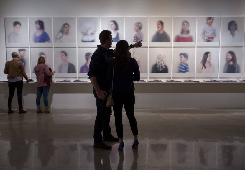 two people standing looking at portraits on wall