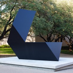 A black sculpture with trees behind