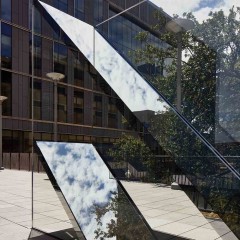 An image of Sarah Oppenheimer's "C-010106" which includes two glass planes which reflect the sky.