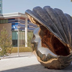 A large bronze shell with a woman walking by