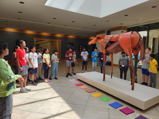 A group of students surround Deborah Butterfield's "Vermillion" a horse sculpture made from scrap metal.