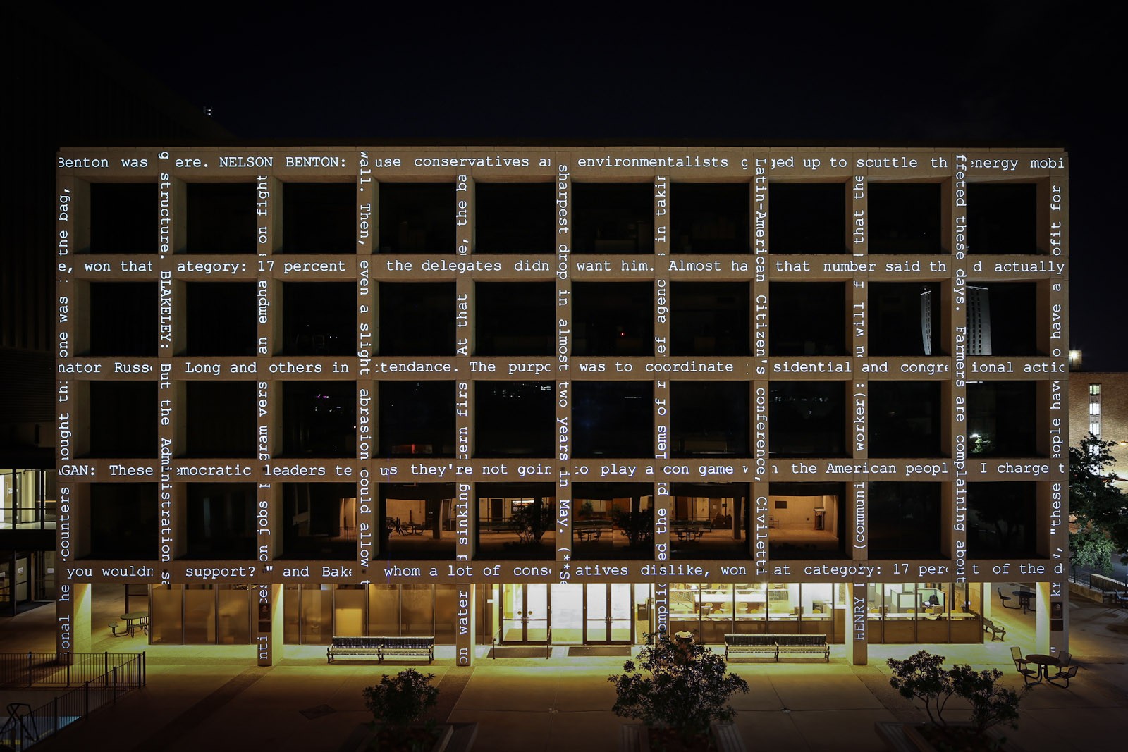 A grid-like building which has text projected across the facade. 