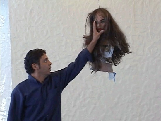 A man grabbing the face of a piñata resembling the top half of a woman