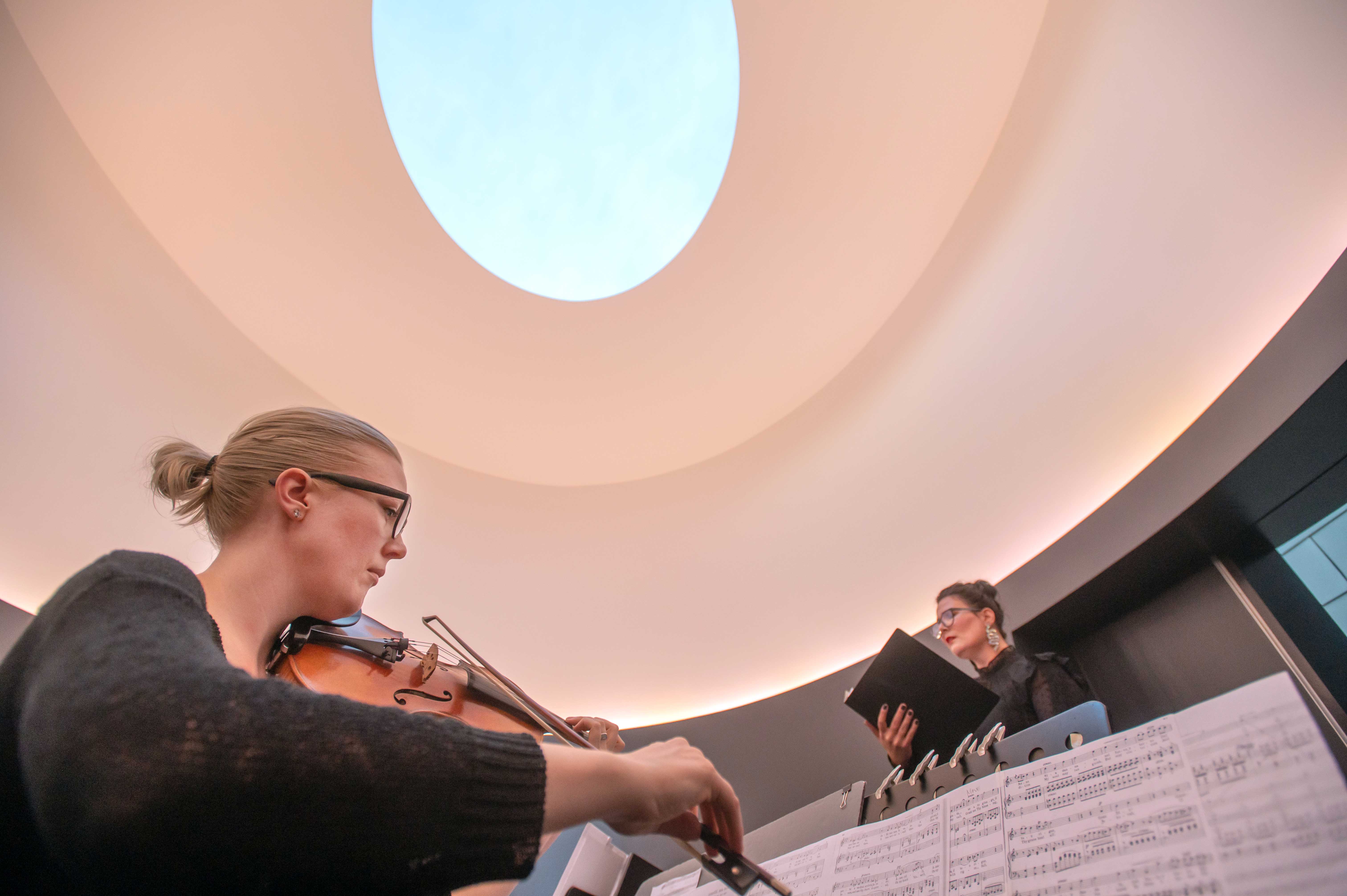 Two musicians perform under the oculus of James Turrell's 