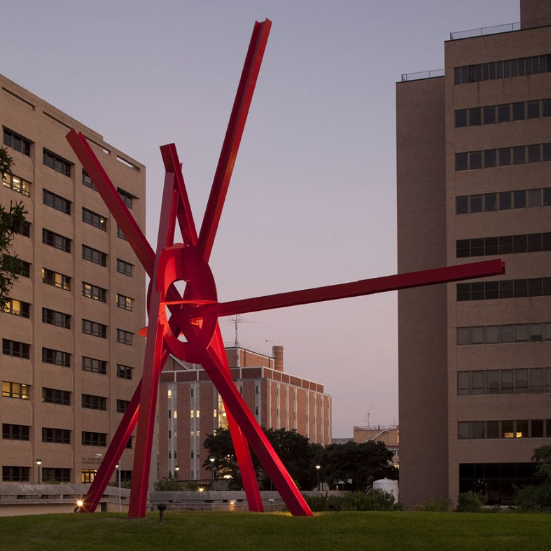 "Clock Knot" is a large red sculpture made of I-Beams which extend out and meet at a central point which visually looks like a knot of string