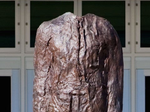 Headless statue in front of a large building