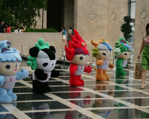 Small cherubit Olympic mascots with a woman walking by