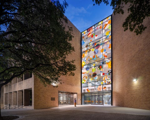 A person in front of a building with a glass facade full of colorful circles