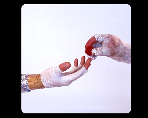 A hand with fingerless gloves reaching out to a hand with dried paint on it