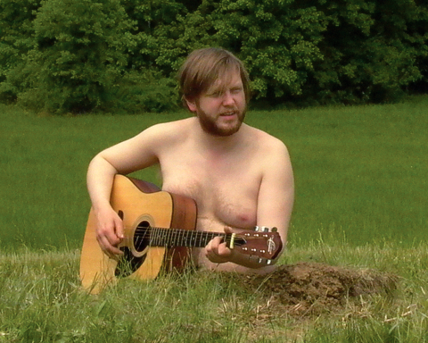 man playing guitar in field