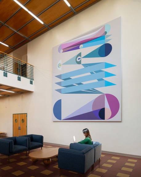 A person sitting on a couch in front of a large geometric painting