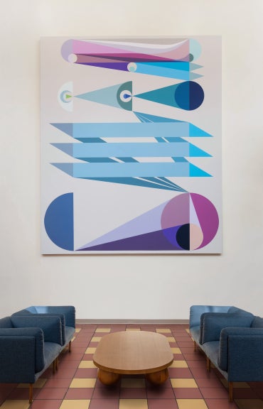 A large geometric painting hangs on the wall in front of two couches