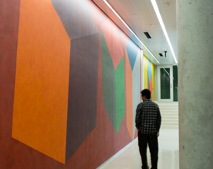 side view of person walking by colored wall