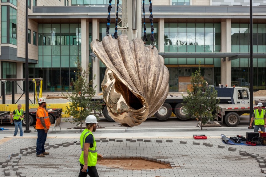 A bronze shell hanging from a crane