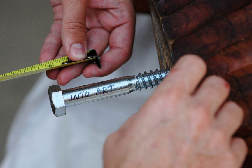 A man holding a bolt with "into art" written on it
