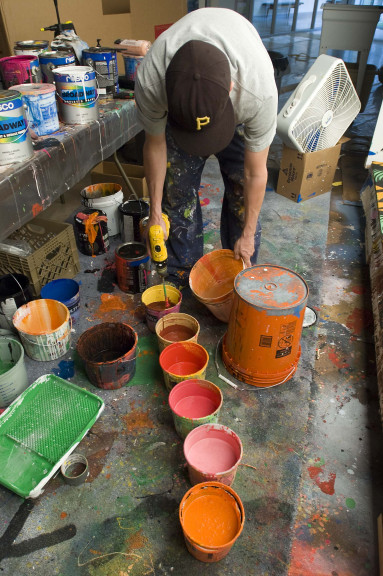 person leaning over paint cans