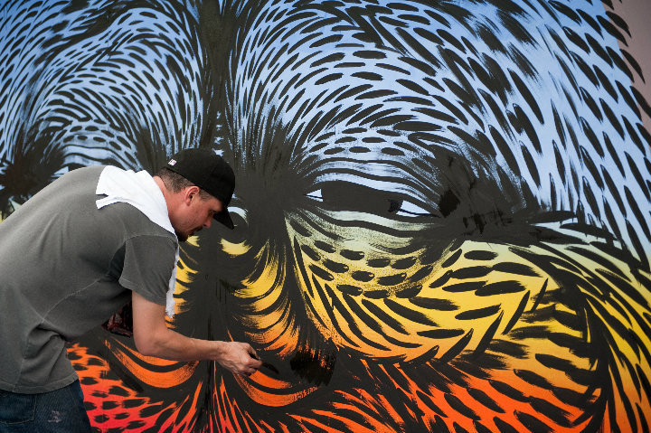 person leaning down painting mural 