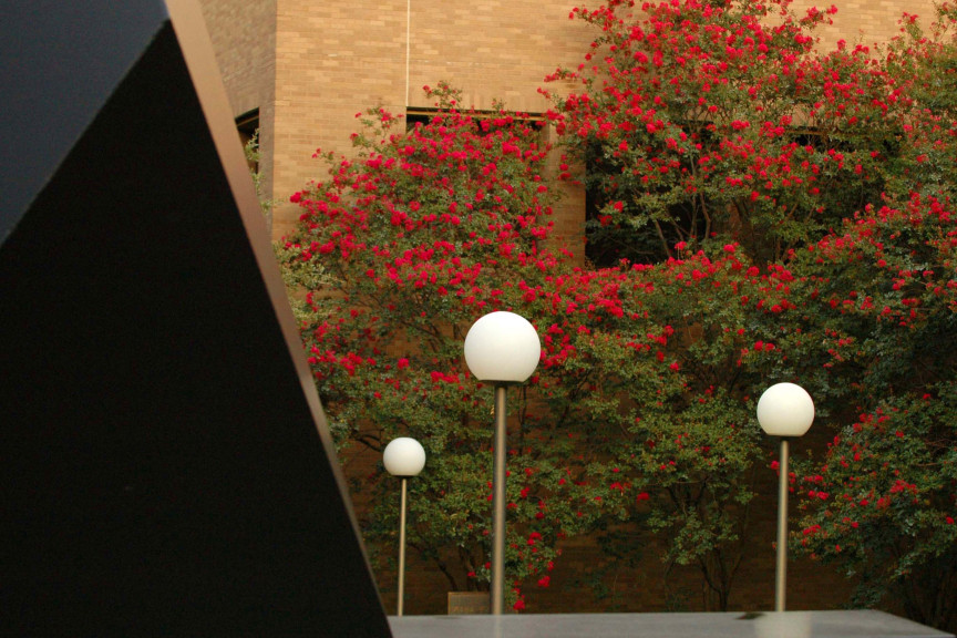 black sculpture on right, lamps and seasonal blossoms behind