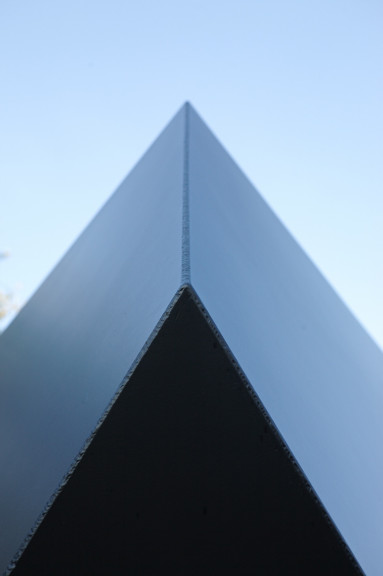 Black triangular shape pointed into middle top of frame with blue sky in background