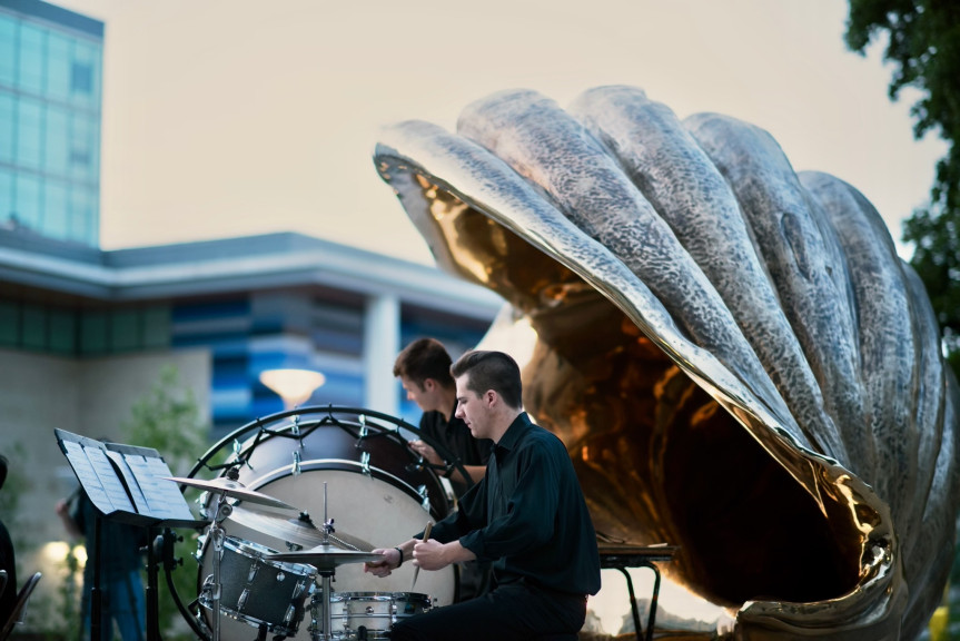 A drummer plays under the curve of Marc Quinn's "Spiral of the Galaxy," a monumentalized shell. 