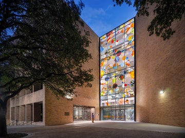 A person in front of a building with a glass facade full of colorful circles