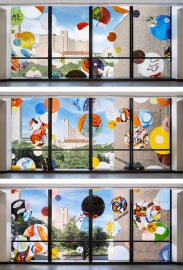 A three-floor, stacked interior view of "Autobiography: Circles" featuring colored circles on a window facade