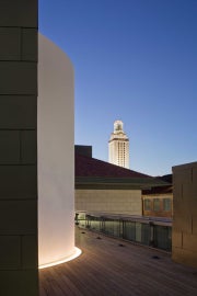 A cylindrical building on a roof with a tower in the background 