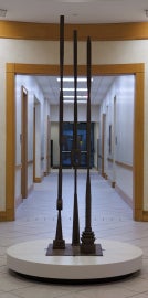 A tall sculpture with three large vertical poles