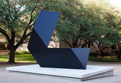 A black sculpture with trees behind