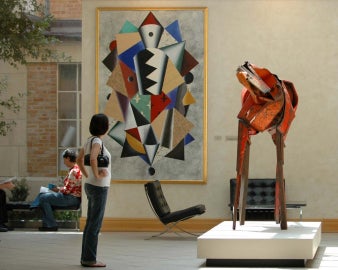 A person standing looking at a red horse sculpture indoors