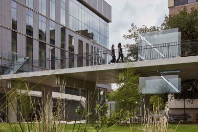 An image of Sarah Oppenheimer's "C-010106," two works cut through the surface of a pedestrian bridge. Seen from the side here, two women walk on the upper surface of the bridge near the work.