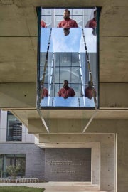 A detail of Sarah Oppenheimer's "C-010106," which shows the reflective quality of the work under the bridge. A man stands on the surface of the bridge and is reflected within the work.
