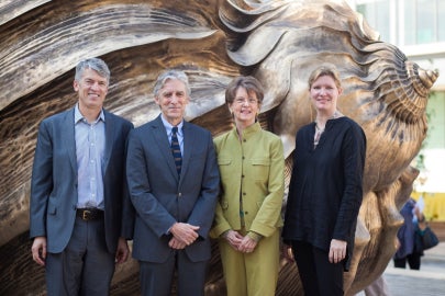 Four people standing in front of a bronze shell