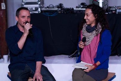 two people speaking to each other sitting on stage