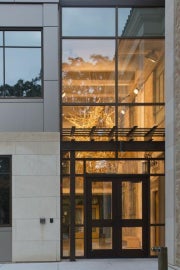 A hanging sculpture made out of wooden crutches behind a large glass window