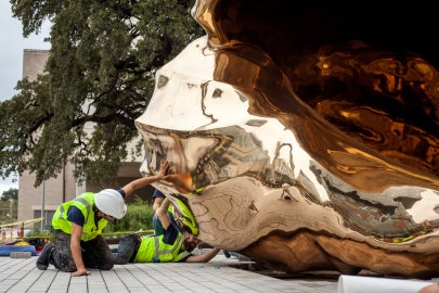 A bronze shell on the ground with crew members around it