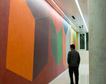 side view of person walking by colored wall