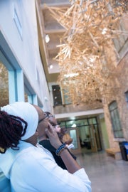 A woman looking at a hanging sculpture made of crutches