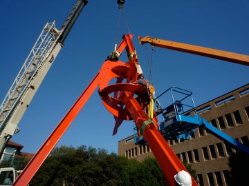 A large red metal sculpture and a crane