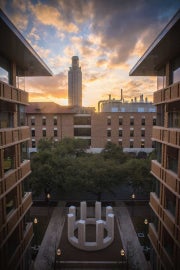 A concrete structure with a large clock tower in the sunset
