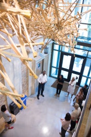 A hanging sculpture made of crutches with people standing underneath