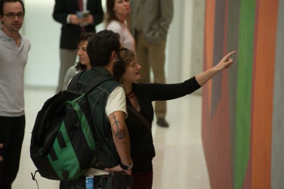 Two people reaching out toward a wall mural