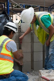 two people leaning down and touching bricks