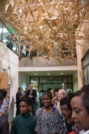 People standing underneath a hanging sculpture made of wooden crutches