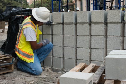person leaning down touching bricks