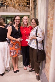 Three women standing under a sculpture