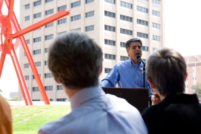 A man talking in front of a large red sculpture