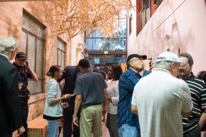 People socializing underneath a hanging sculpture made of crutches