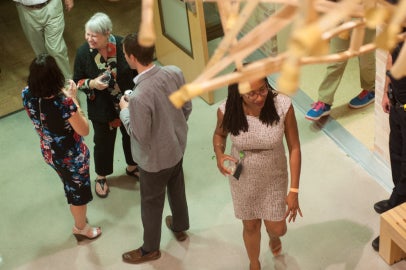 People standing underneath a hanging sculpture made out of wooden crutches